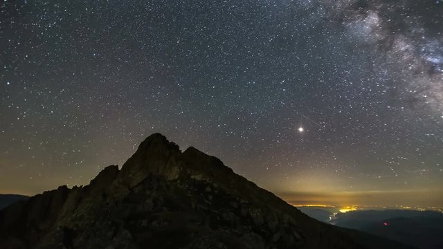 Milky way over mountain peak with city lights in the background 