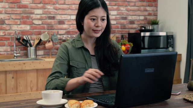 Woman using breakfast and laptop at the same time.
