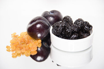 Raisins, plums and prunes on white background