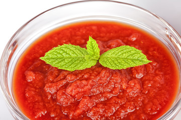 A glass bowl full of tomato sauce with mint leaves