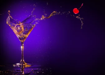 Gordijnen rode kers spatten uit een martini-glas op een paarse achtergrond © popout