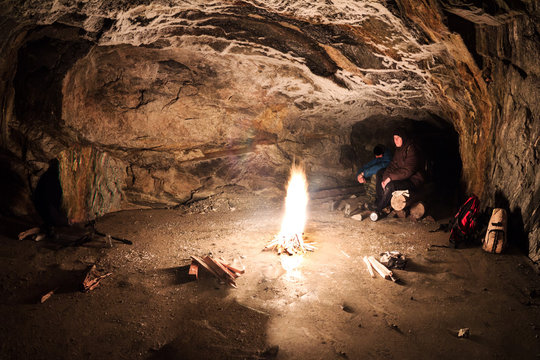 Foto Stock Survival in extreme conditions. Kindling a fire to warm in a  stone cave | Adobe Stock