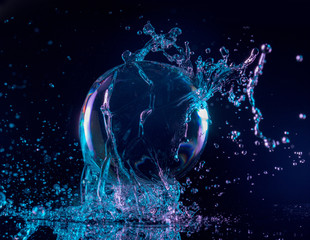 Fototapeta na wymiar blue and purple water splashing on a transparent ball in a dark background