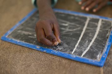 Mano de niño pintando en pizarra en una escuela de Gambia, Africa