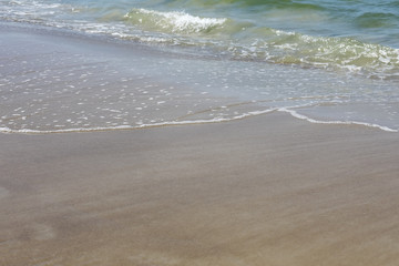 Fototapeta na wymiar The gentle waves reach the beach shore