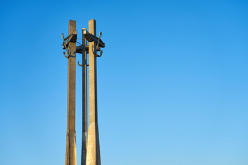                      Three Crosses with anchors, a monument to the fallen workers of shipyard at Solidarnosti Square in Gdansk, Poland against a blue clear sky. Copy space for text.  