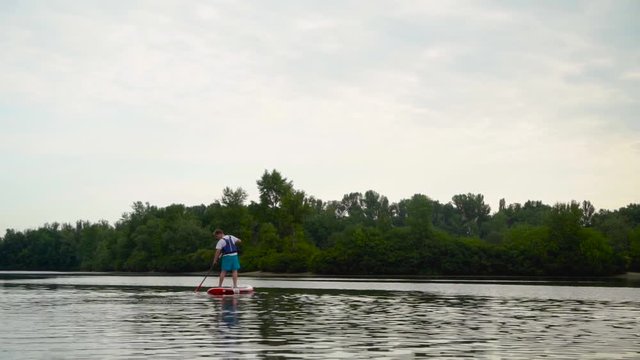 Handsome youmg man swims standing on a kayak