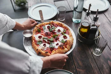 Foto op Canvas bijgesneden opname van vrouw met bord met heerlijke pizza margherita om op tafel in restaurant te serveren © LIGHTFIELD STUDIOS