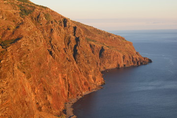 cliffs reflecting the red light of the sunset at the ocean