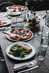 tasty italian dishes and drinks on wooden rustic table at restaurant