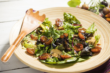 Salat mit gedünsteten Honig-Balsamico-Zwetschken (Zwetschgen), Champignons, Mandeln und Kresse auf Holzteller serviert