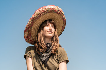 Young beautiful girl in sombrero and bandana dressed up as bandit of gangster. Female person in traditional mexican hat posing as mexico festive symbol or for halloween costume idea