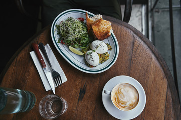 top view of healthy salad with sprouts and eggs on wooden table at restaurant with cup of coffee