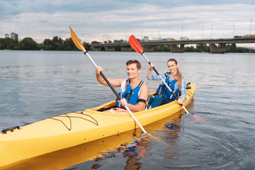 Strong man. Handsome strong man feeling amazing while teaching his girlfriend kayaking