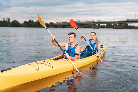 Strong man. Handsome strong man feeling amazing while teaching his girlfriend kayaking