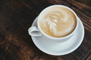 cup of fresh coffee with latte art on rustic wooden table