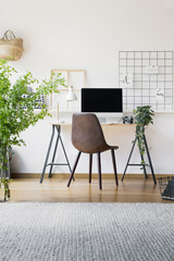 Inspirational organizer in a hipster workspace interior with a stylish, leather chair by a tall,...