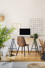Modern computer screen on an industrial desk by a white wall in a warm, sunny study space of a...