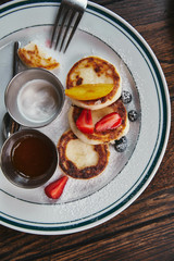 top view of delicious syrniki on plate and on rustic wooden table