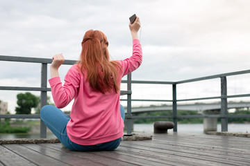 Favourite music. Pleasant young woman holding her smartphone while listening to music