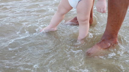The little baby's feet touched in to the sea with parents