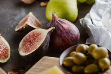 close up view of figs, olives in bowl and pear arranged on tabletop