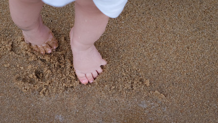 The little cute baby's feet walking on the wet sand.