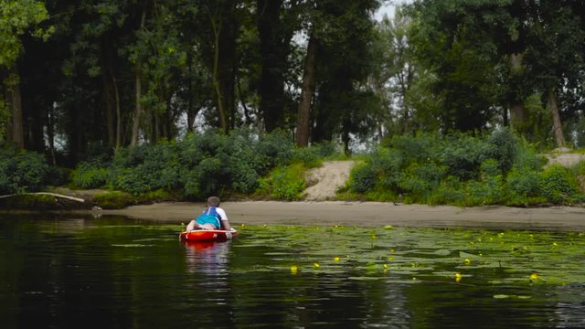 Young guy is lying on a kayak near the shore