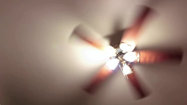 A ceiling fan spinning on high with the lights on.