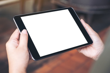 Mockup image of woman's hands holding black tablet pc with blank desktop screen in cafe