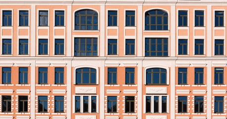 Beautiful facade of a building with yellow walls and white decor on the windows