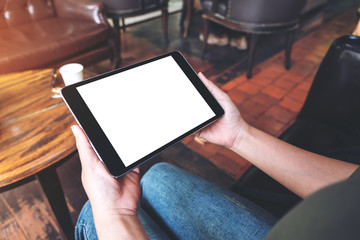 Mockup image of woman's hands holding black tablet pc with blank desktop screen while sitting in cafe