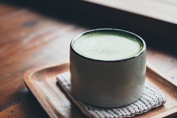 A cup of hot matcha latte on wooden floor