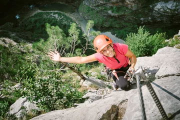 Foto auf Acrylglas Junge glückliche Frau, die einen Klettersteig entlang klettert © Stillkost