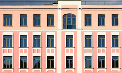 The facade of the old building with pink walls and white decor on the windows