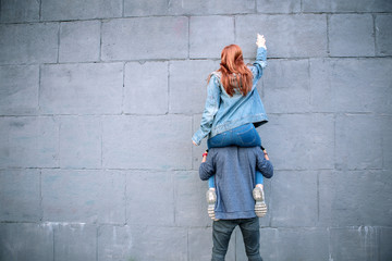Obraz na płótnie Canvas Creative graffiti. Nice strong man holding his girlfriend while helping her to draw a graffiti