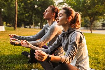 Fitness loving couple friends in park make meditate exercises. - obrazy, fototapety, plakaty