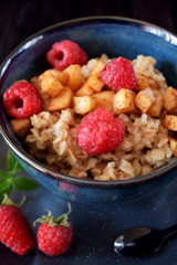 Porridge with apples, raspberries and honey topped with mint. Healthy breakfast meal