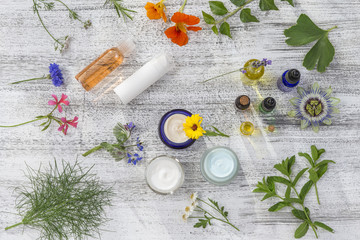 Herbal cosmetic ingredients top view wooden background. Mix of flowers , herb-infused oil, aroma dropper essential oil bottle,on old white wooden background. top view