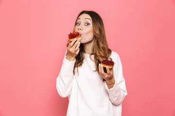 Fotobehang Portrait of a satisfied young woman eating pastry © Drobot Dean