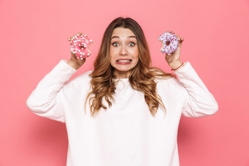 Portrait of a confused young woman showing donuts