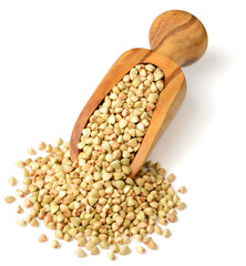 uncooked buckwheat in the wooden scoop, isolated on the white background.