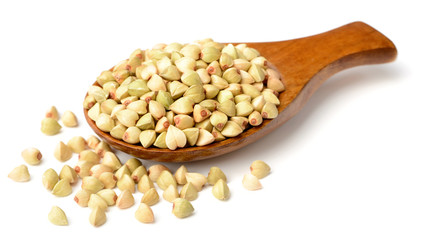 uncooked buckwheat in the wooden spoon, isolated on the white background.