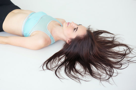Young woman with pretty hairstyle wearing sportswear lying on the floor