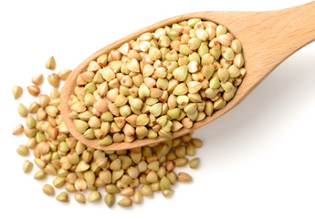 uncooked buckwheat in the wooden spoon, isolated on the white background.