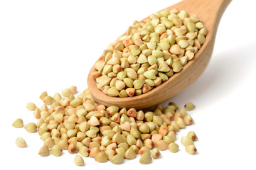 uncooked buckwheat in the wooden spoon, isolated on the white background.