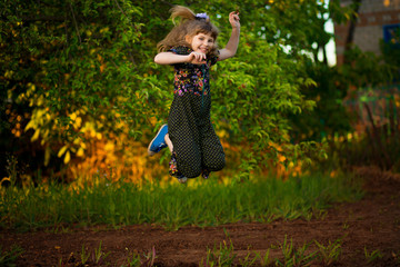 Portrait of adorable smiling girl jump in park at sunset. Child happy that autumn has come