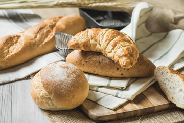 fresh bread and wheat on sack and wooden table.