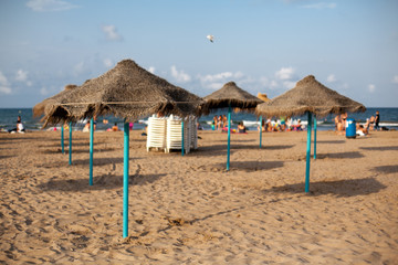Straw umbrellas on seaside in sunset light. Sand beach in Valencia. Blue sky. Copy space.