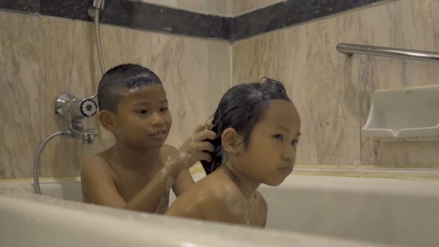 Asian brothers and sisters swim in the bathtub and wash their hair happily.